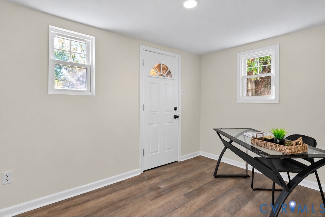 Neutral-toned walls paired with wood-finish flooring, two double-hung windows, and a single-entry door with a semi-circular glass insert
