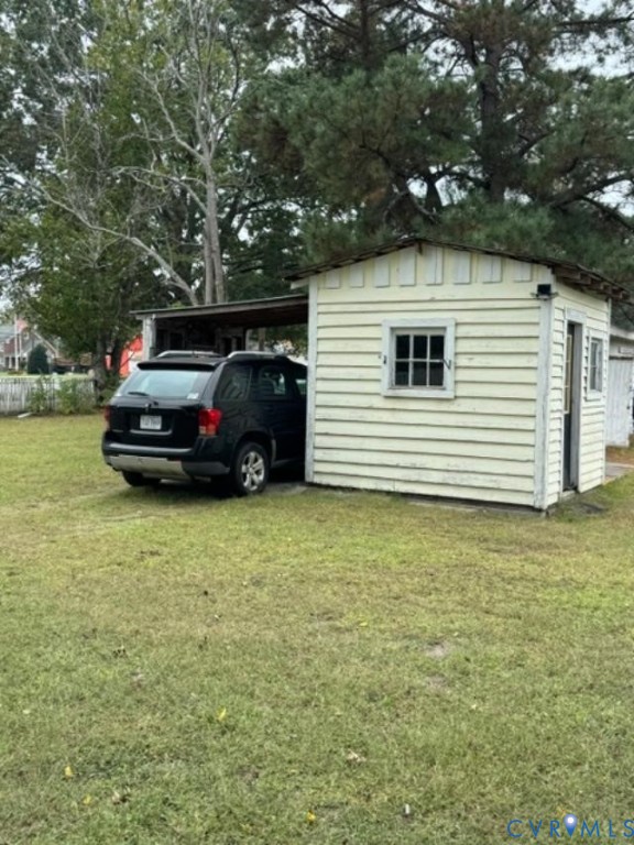 Detached outbuilding featuring horizontal lap siding, a covered storage area, and multi-pane window glazing