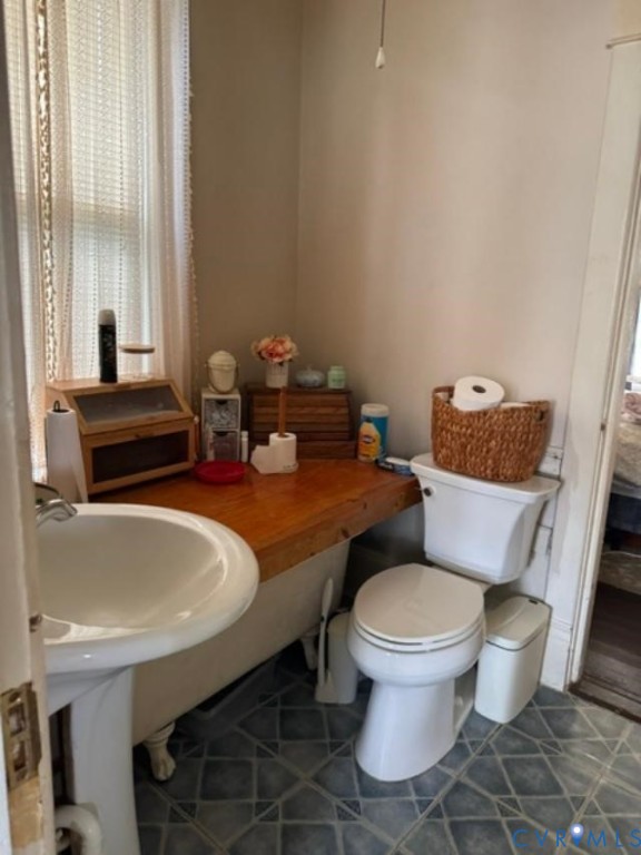 Claw-foot tub, white pedestal sink, and patterned flooring