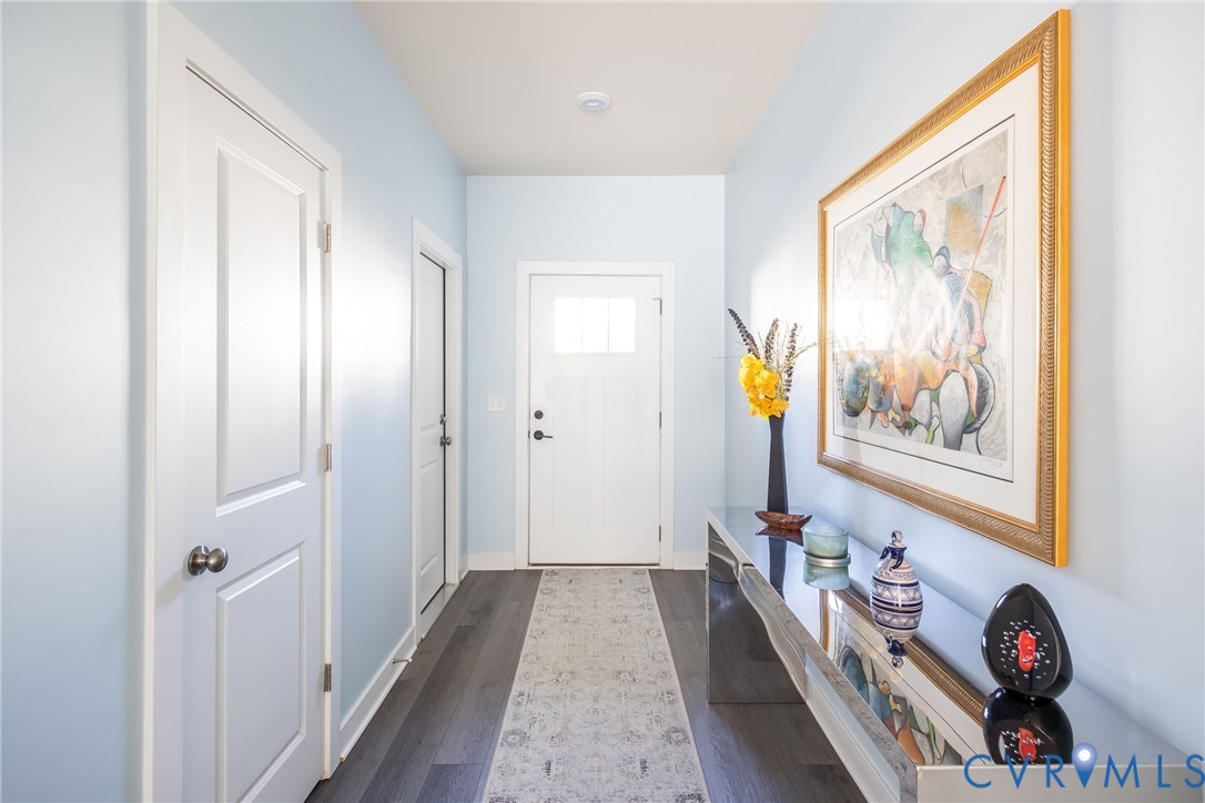 Open interior space featuring light-toned wall paint, wood-finish flooring, a multi-blade ceiling fan, and a staircase with white balusters Open interior space featuring light-toned wall paint, wood-finish flooring, a multi-blade ceiling fan, and a staircase with white balusters