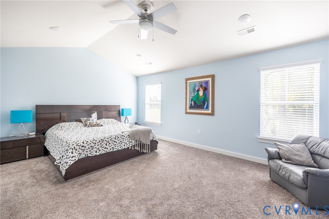 Spacious room featuring a vaulted ceiling, wall-to-wall carpeting, and multiple windows with installed blinds Spacious room featuring a vaulted ceiling, wall-to-wall carpeting, and multiple windows with installed blinds
