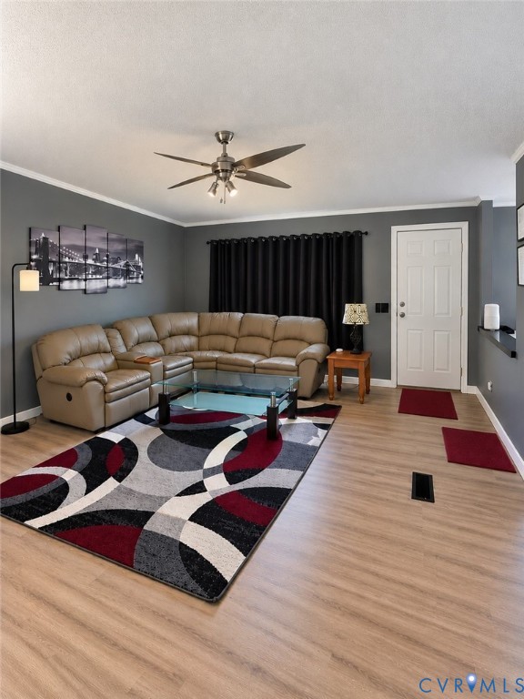 Living area featuring wood-finish flooring, a multi-blade ceiling fan with integrated lighting, and a six-panel entry door Living area featuring wood-finish flooring, a multi-blade ceiling fan with integrated lighting, and a six-panel entry door