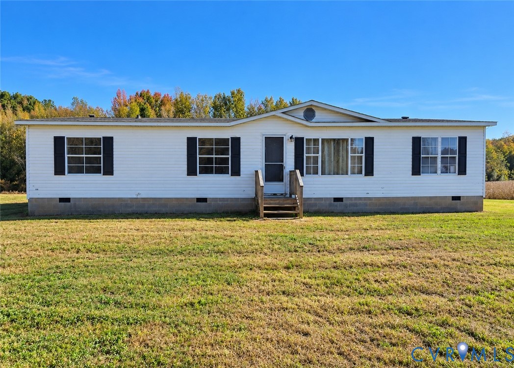 Single-level exterior featuring white siding, contrasting shutters, a gable roofline, and a concrete block foundation Single-level exterior featuring white siding, contrasting shutters, a gable roofline, and a concrete block foundation