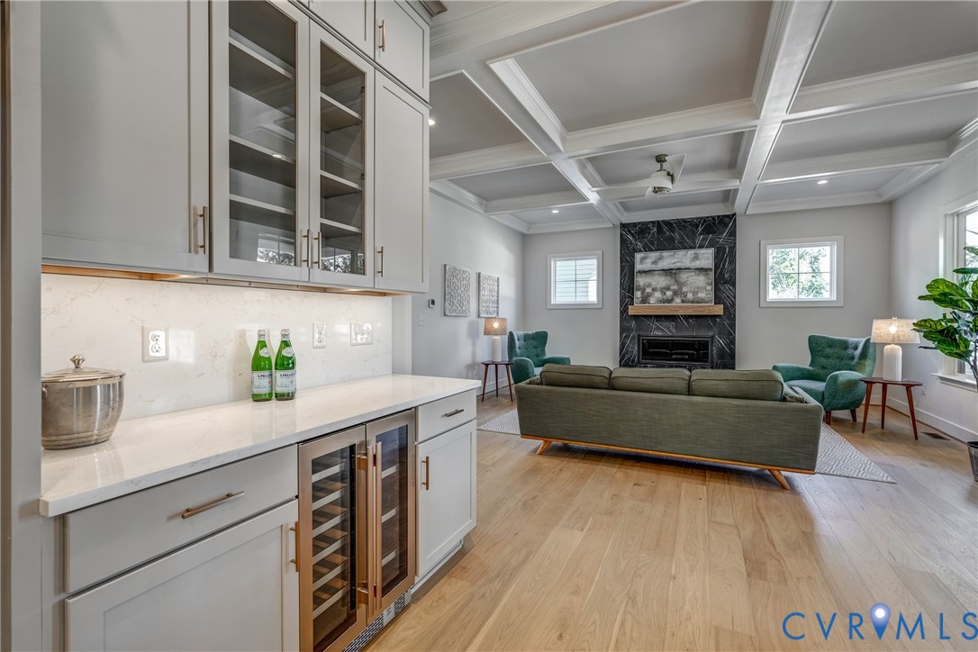Coffered ceilings, wood-finish flooring, built-in cabinetry with glass-front uppers, quartz countertops, and a full-height stone-surround fireplace Coffered ceilings, wood-finish flooring, built-in cabinetry with glass-front uppers, quartz countertops, and a full-height stone-surround fireplace