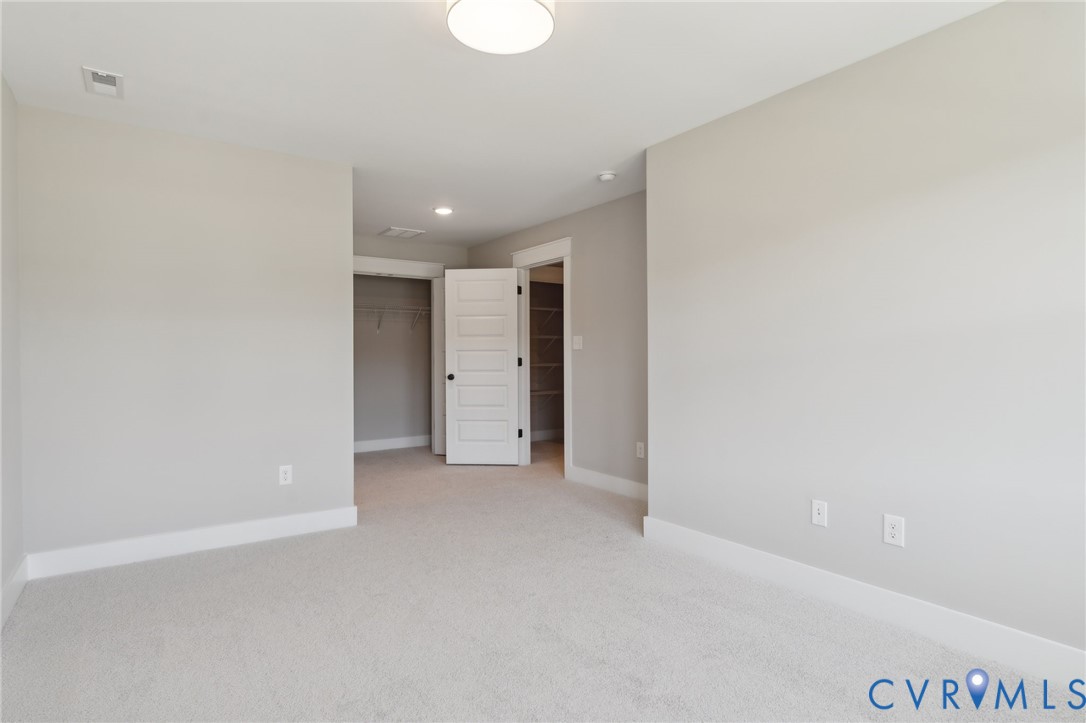Neutral interior featuring wall-to-wall carpeting, a four-panel interior door, and built-in closet shelving
