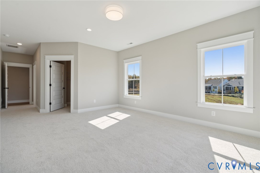 Neutral wall tones, wall-to-wall carpeting, multi-pane windows with detailed casing, recessed and flush-mount overhead lighting, and multi-panel interior doors