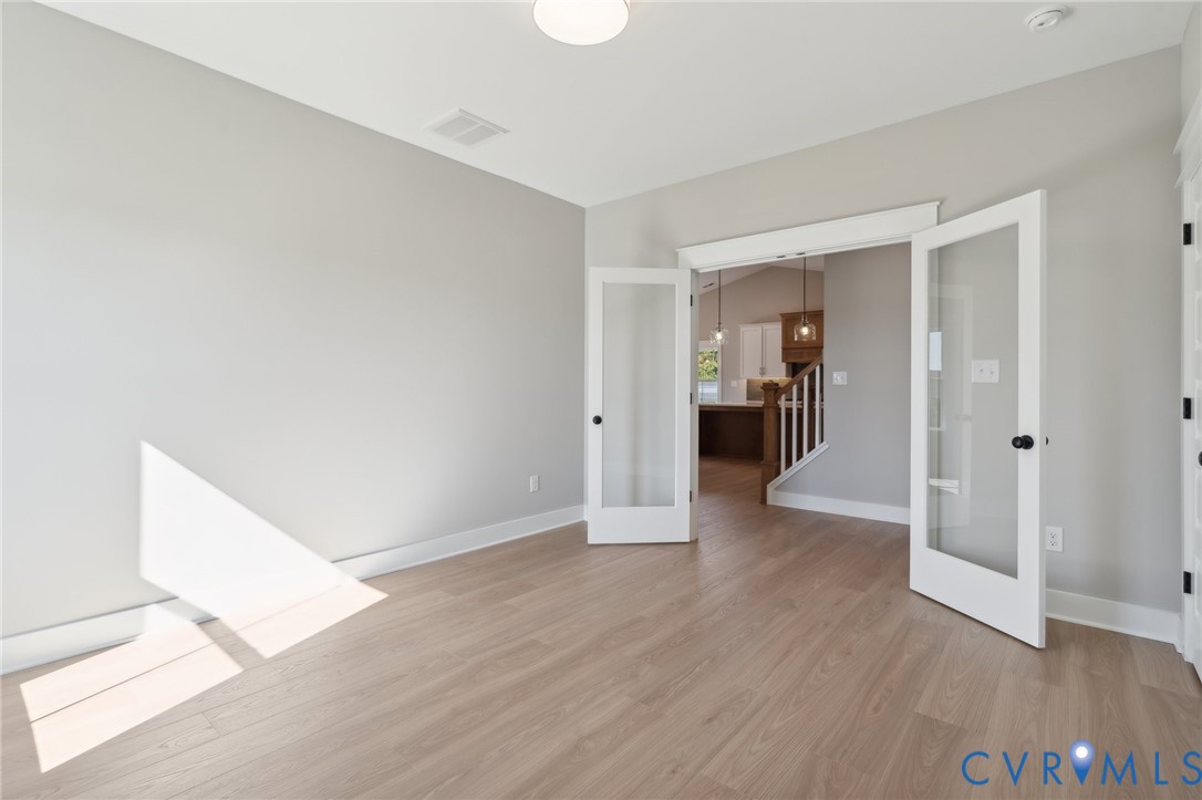 Neutral-toned interior space featuring wood-finish flooring and white French doors with glass panes