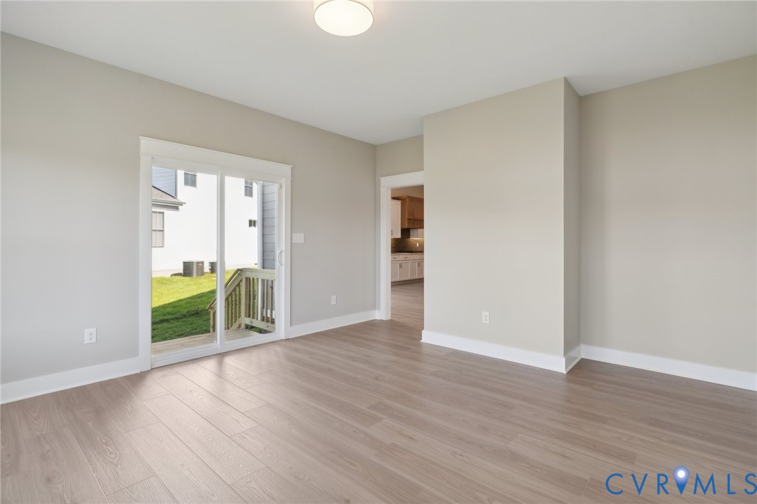 Neutral interior featuring wood-finish flooring, sliding glass door, flush-mount ceiling lighting, and crisp wall finishes
