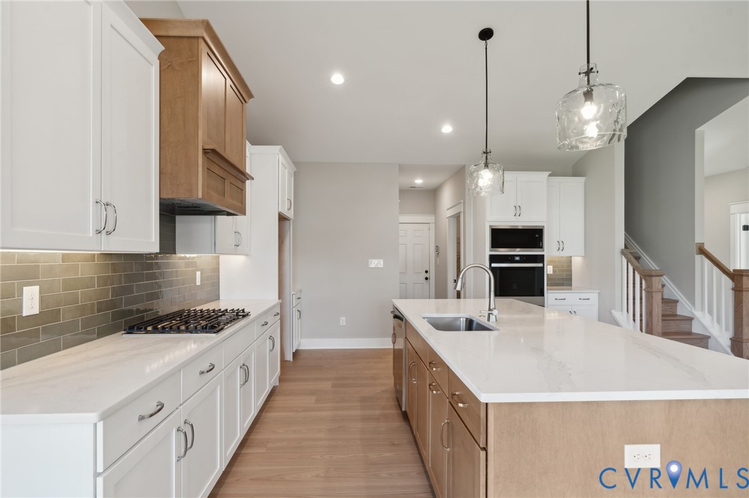 Kitchen featuring two-tone cabinetry, quartz countertops, a subway tile backsplash, a gas cooktop, and built-in wall oven