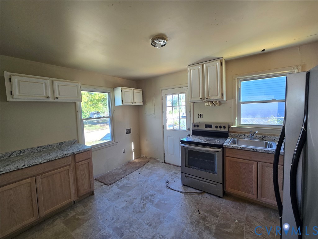 Kitchen featuring stone-finish countertops, stainless steel range, dual-tone cabinetry, and tile flooring Kitchen featuring stone-finish countertops, stainless steel range, dual-tone cabinetry, and tile flooring