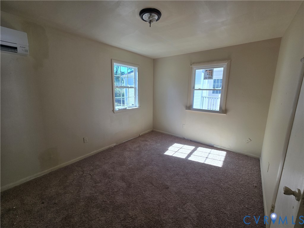 Wall-mounted ductless HVAC unit, double-hung windows with muntin grids, and wall-to-wall carpeting Wall-mounted ductless HVAC unit, double-hung windows with muntin grids, and wall-to-wall carpeting