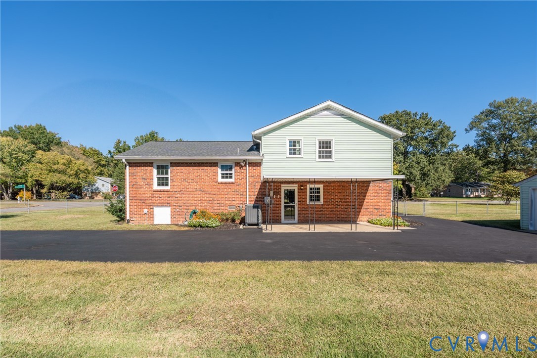 Exterior featuring a combination of brick and lap siding, a covered concrete patio, and an asphalt driveway