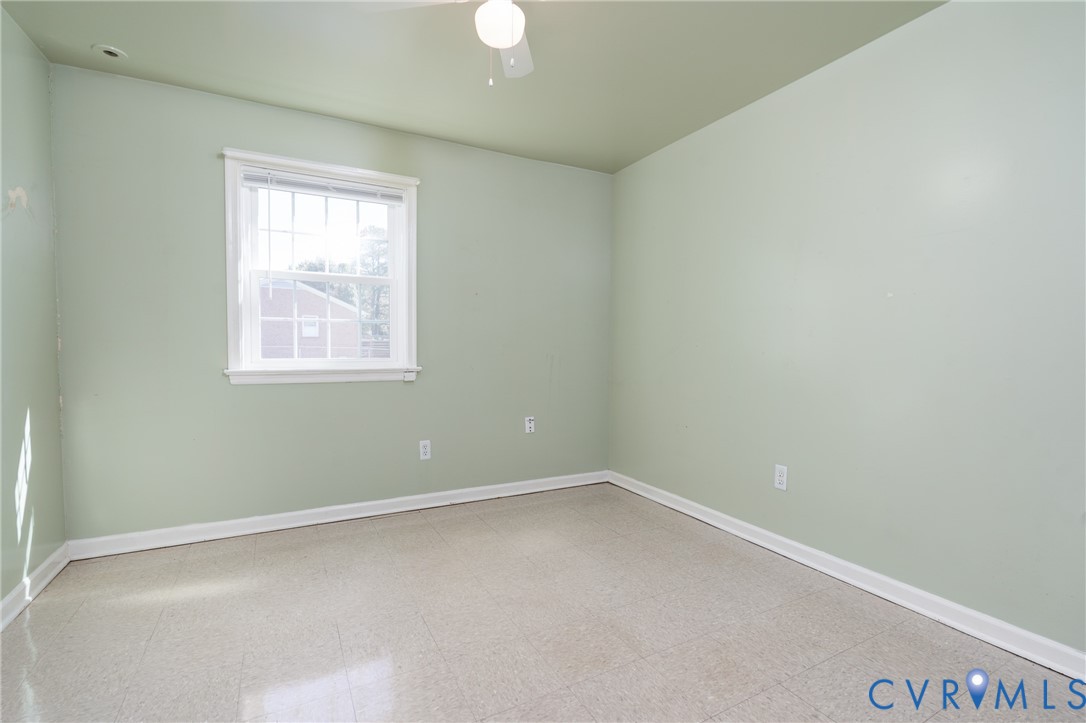 Room featuring neutral-toned flooring, solid-colored wall surfaces, a white-framed single-hung window, and a ceiling-mounted light fixture with a fan