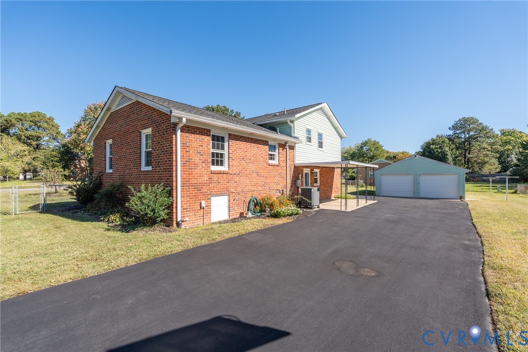 Brick exterior, asphalt driveway, detached two-car garage, and covered patio