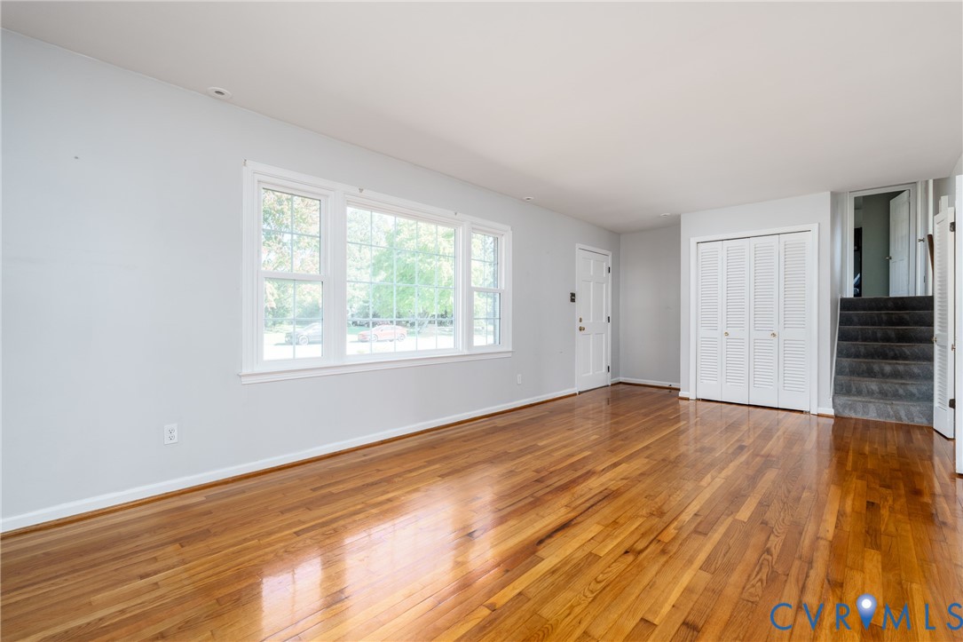 Living area featuring wood-finish flooring, large multi-pane windows, and white bifold closet doors