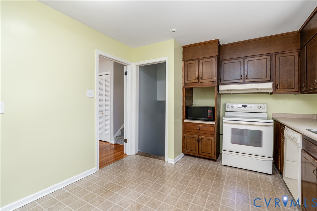Kitchen featuring stained wood cabinetry, white electric range, integrated hood, and tile flooring