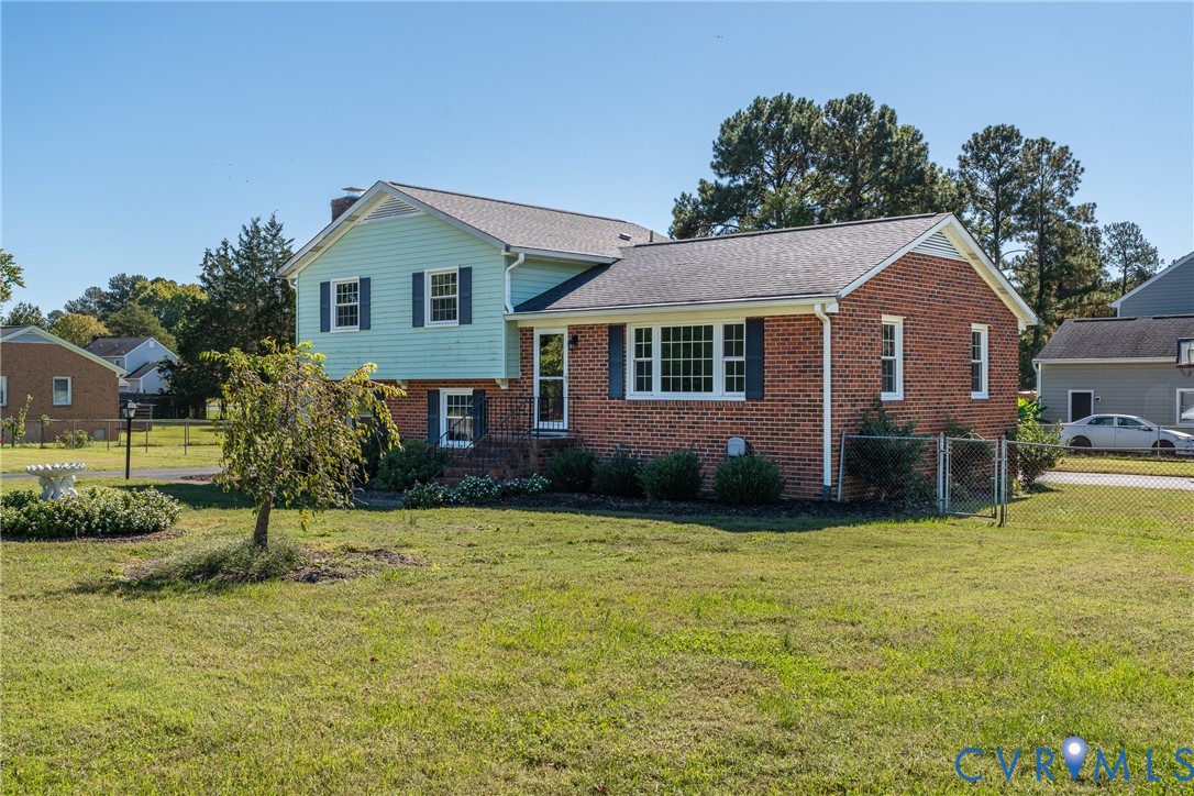 Two-story brick and lap siding exterior featuring multi-pane windows, a gabled roofline, and a fenced yard Two-story brick and lap siding exterior featuring multi-pane windows, a gabled roofline, and a fenced yard