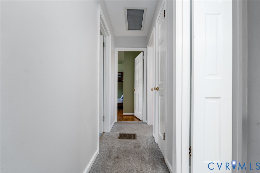 Interior hallway featuring multi-panel interior doors, neutral wall paint, and carpeted flooring