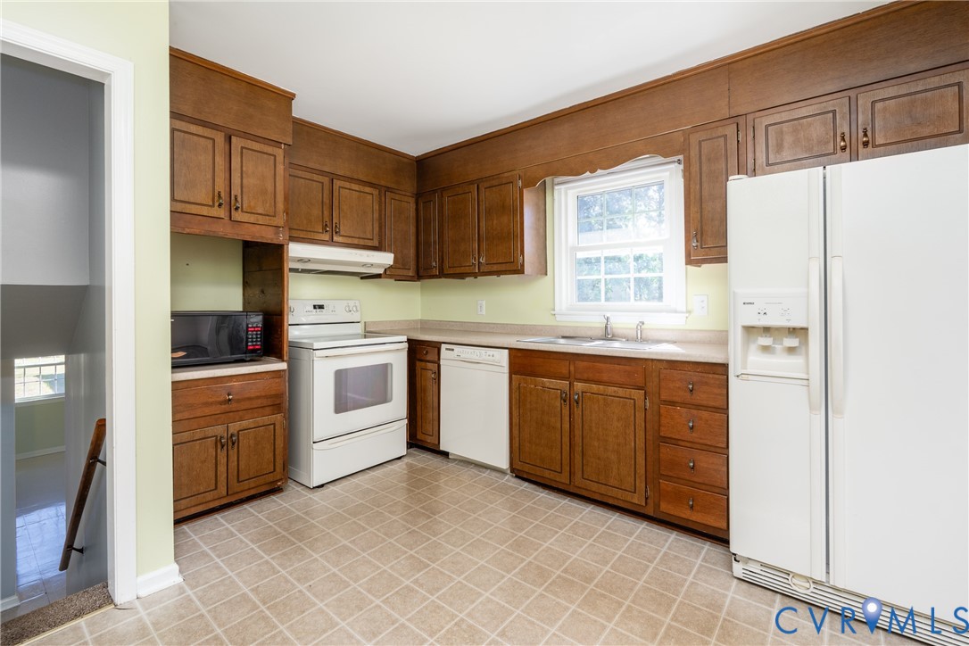 Kitchen featuring natural wood cabinetry, solid surface countertops, and tiled flooring