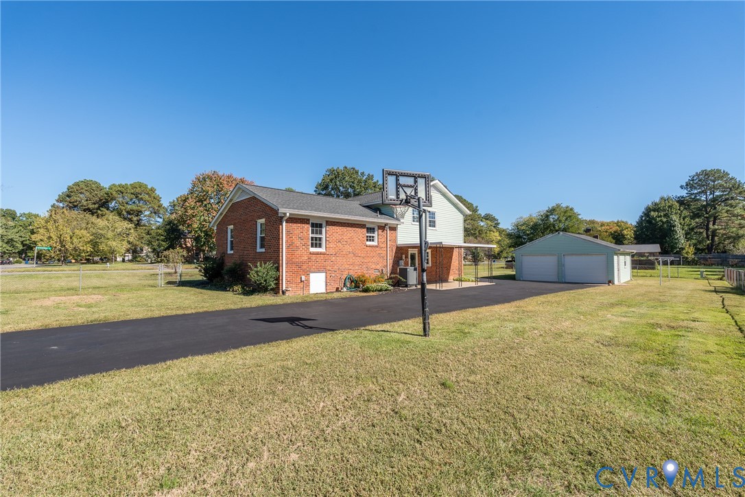 Exterior featuring a brick and siding facade, detached two-car garage, expansive lot, and paved driveway