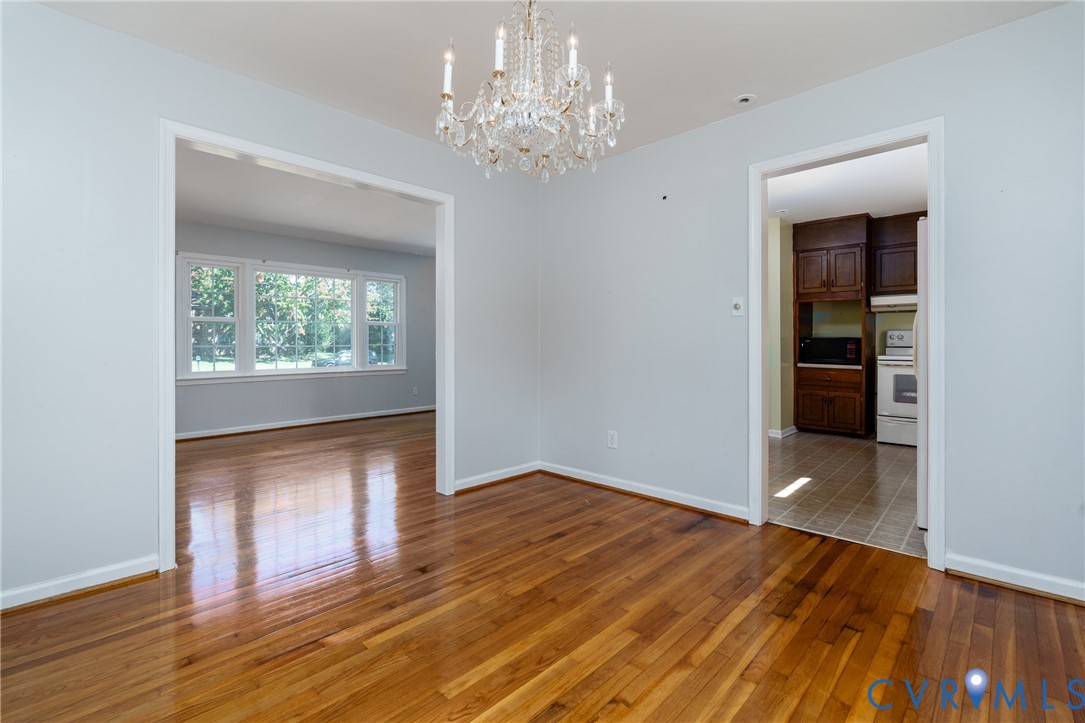 Dining area featuring wood-finish flooring, a decorative crystal chandelier, and neutral wall tones