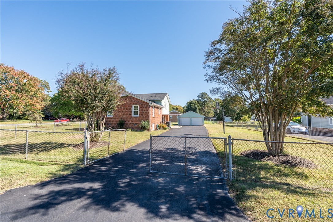 Brick exterior, asphalt driveway, detached two-car garage, and chain-link perimeter fencing