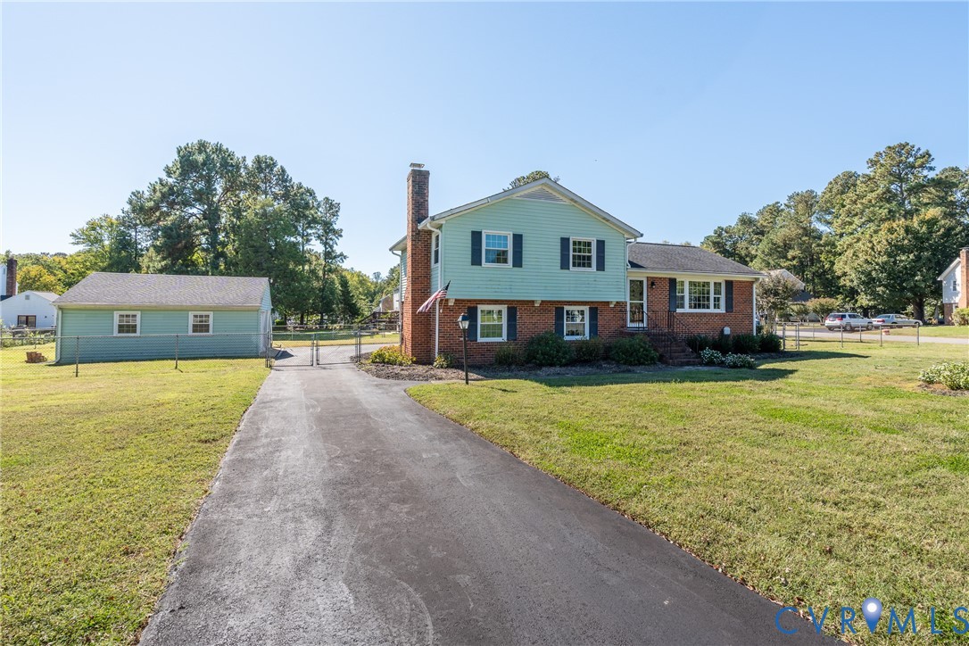 Two-story residence featuring a brick and siding exterior, external brick chimney, asphalt driveway, and detached garage Two-story residence featuring a brick and siding exterior, external brick chimney, asphalt driveway, and detached garage