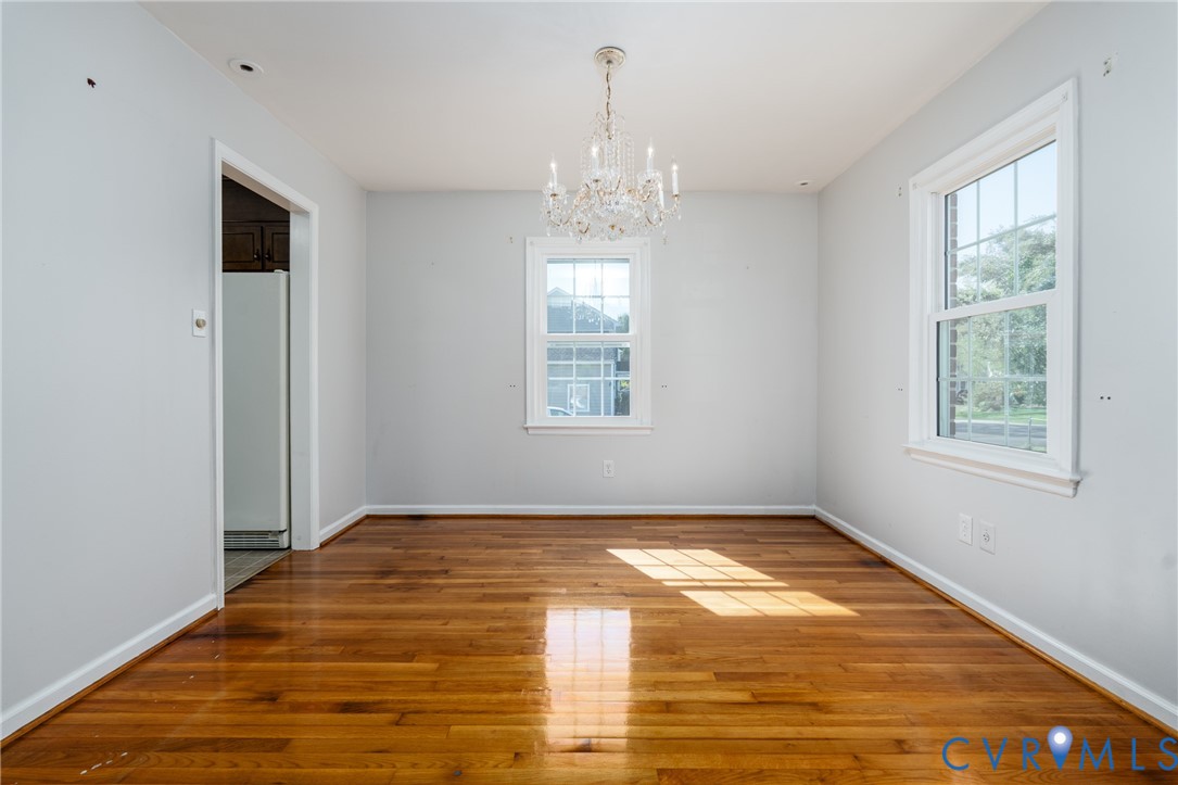 Bright, light-filled room showcasing pristine hardwood flooring, white walls, and abundant natural light from multiple windows