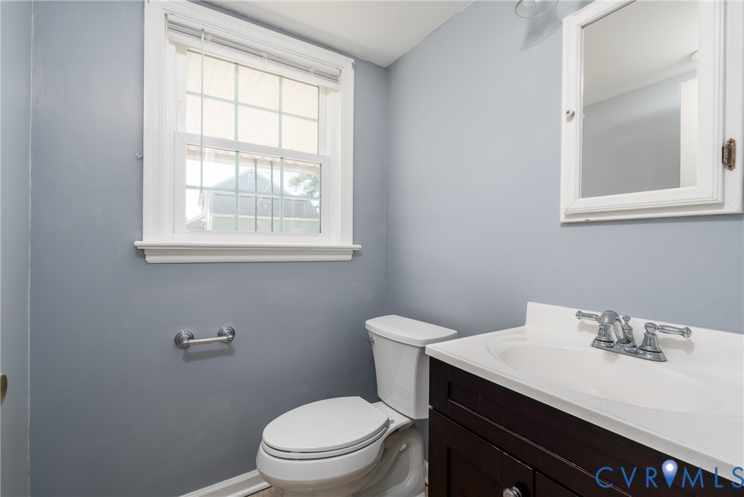 Dark wood vanity with a white countertop, integrated sink, chrome double-handle faucet, and white-framed medicine cabinet