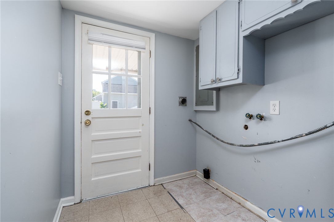Utility area featuring tile flooring, wall-mounted cabinetry, and a glass-panel exterior door