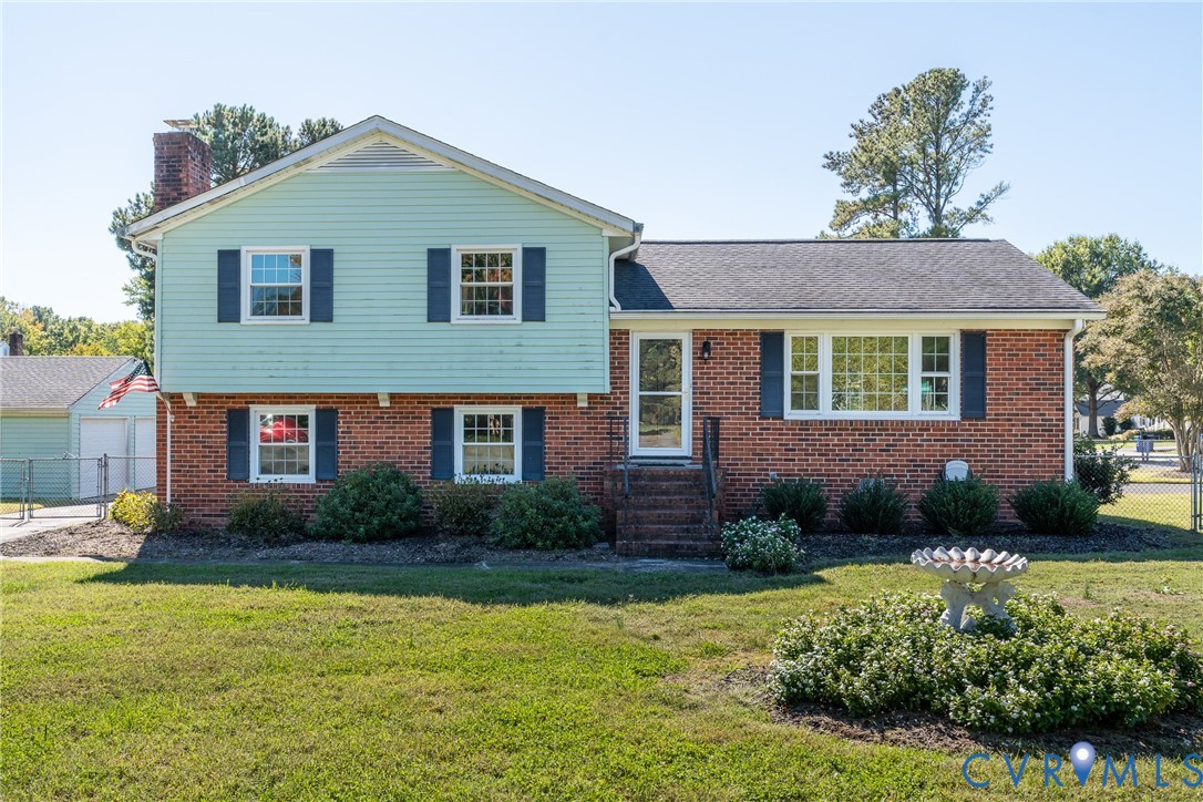 Split-level exterior featuring a brick and siding facade, chimney, dark shutters, and front landscaping Split-level exterior featuring a brick and siding facade, chimney, dark shutters, and front landscaping