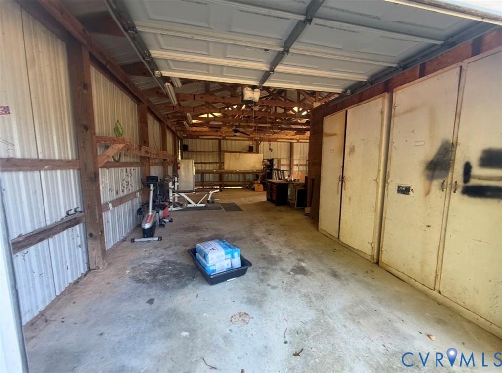 Expansive detached garage featuring corrugated metal wall cladding, exposed timber framing, concrete flooring, and built-in floor-to-ceiling storage cabinetry