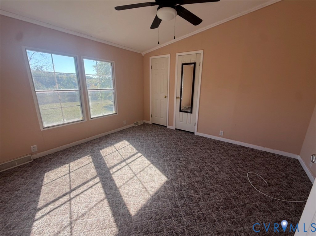 Room featuring a vaulted ceiling, dual windows, patterned wall-to-wall carpeting, and a ceiling-mounted light fixture