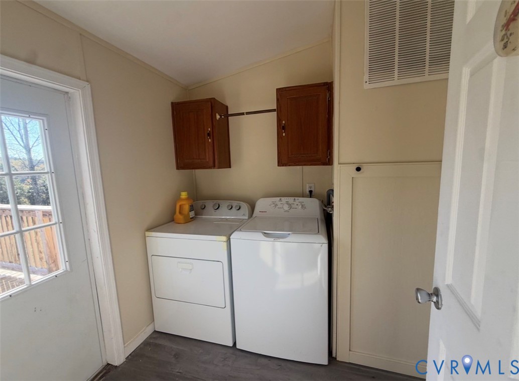 Laundry area featuring wall-mounted cabinetry, wood-finish flooring, and a half-light exterior door