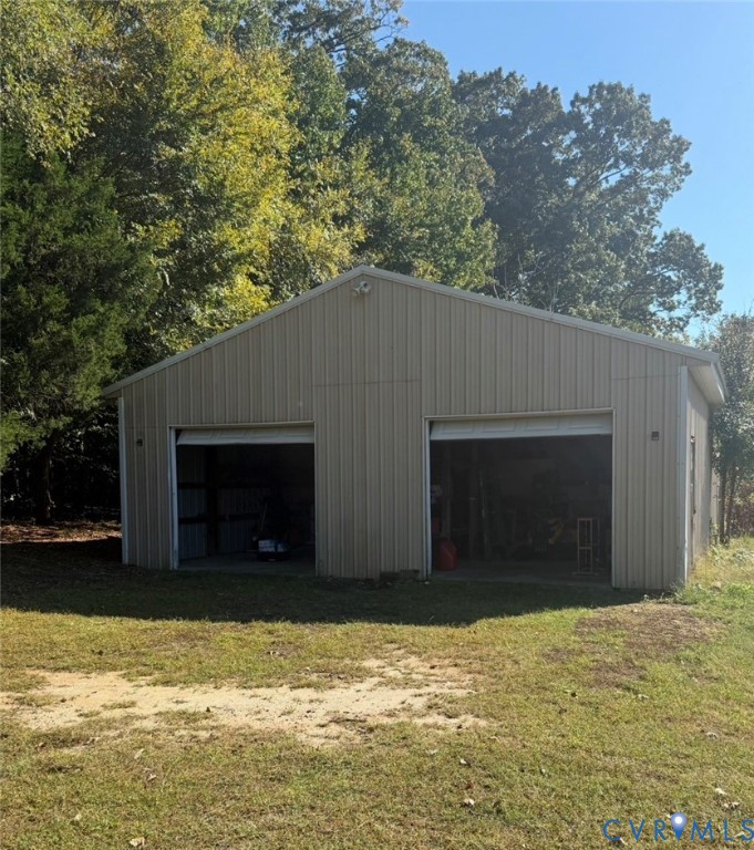 Detached metal-sided structure featuring two garage bays and exterior lighting