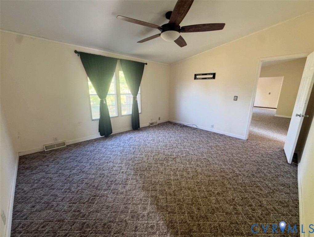 Room featuring vaulted ceilings, a ceiling fan with integrated lighting, patterned wall-to-wall carpeting, and dual-pane windows