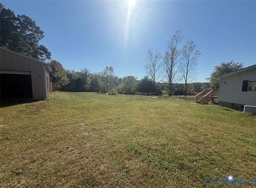 Expansive lot featuring a detached outbuilding, a tiered wood deck, and mature trees
