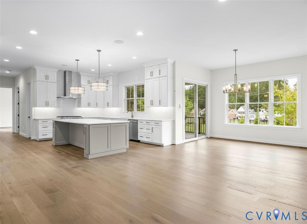 Kitchen featuring white shaker-style cabinetry, center island, stone countertops, recessed lighting, and wood-finish flooring