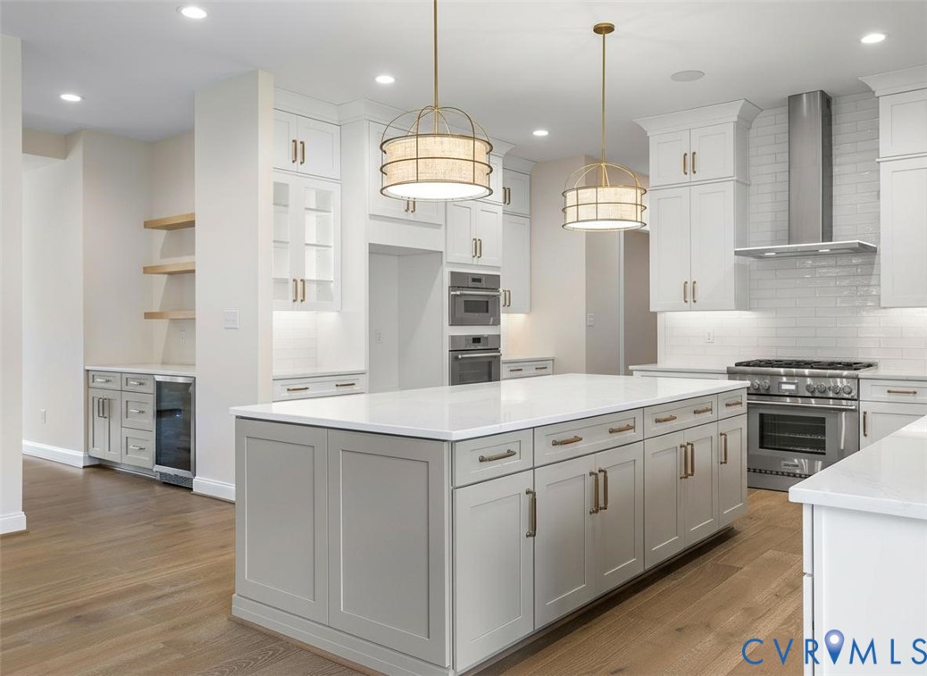 Kitchen featuring a central island with quartz countertops, custom shaker-style cabinetry, stainless steel professional-grade appliances, subway tile backsplash, and wood-finish flooring