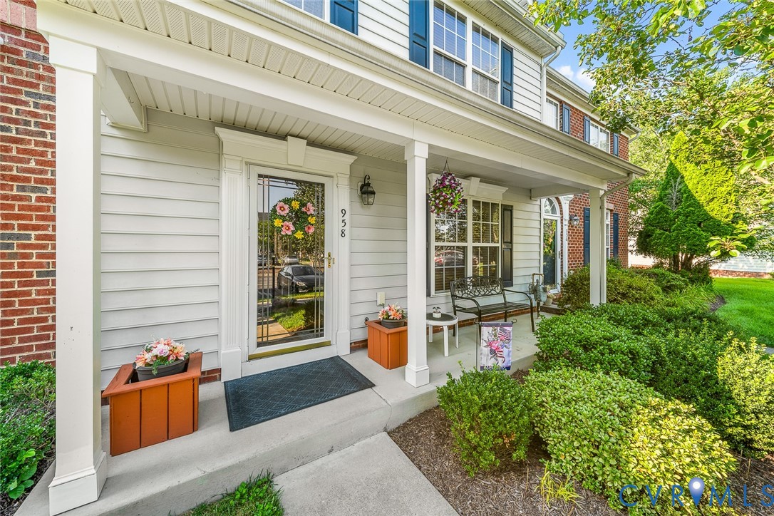 Covered front porch featuring a concrete foundation, square columns, architectural molding around the entryway, and exterior light fixtures Covered front porch featuring a concrete foundation, square columns, architectural molding around the entryway, and exterior light fixtures