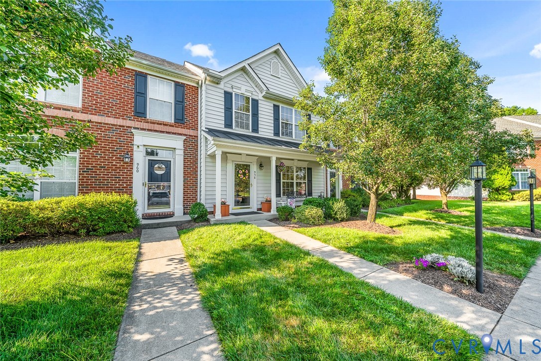 Exterior featuring a brick and siding facade, covered front entry porch, multi-pane windows with shutters, and concrete walkways Exterior featuring a brick and siding facade, covered front entry porch, multi-pane windows with shutters, and concrete walkways