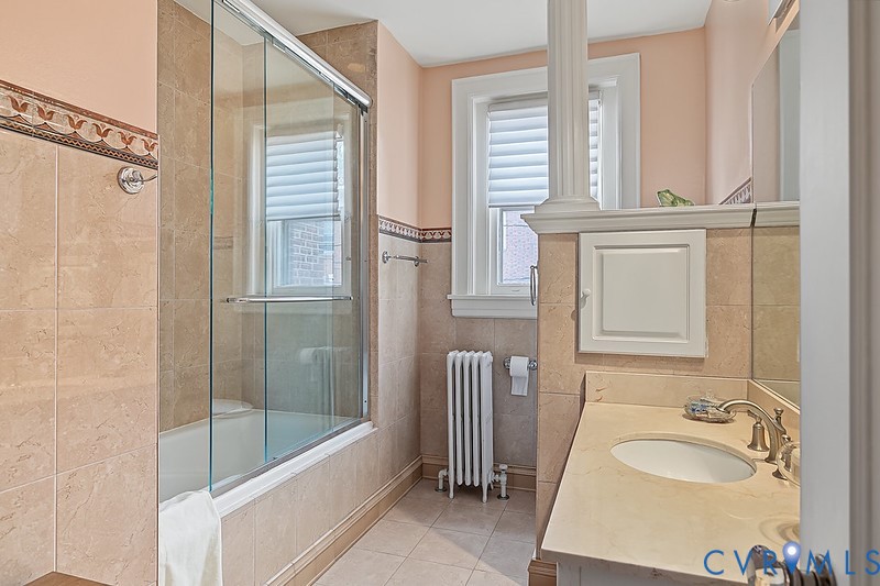 Hall bathroom with shower and tub, tile floor and granite sick.