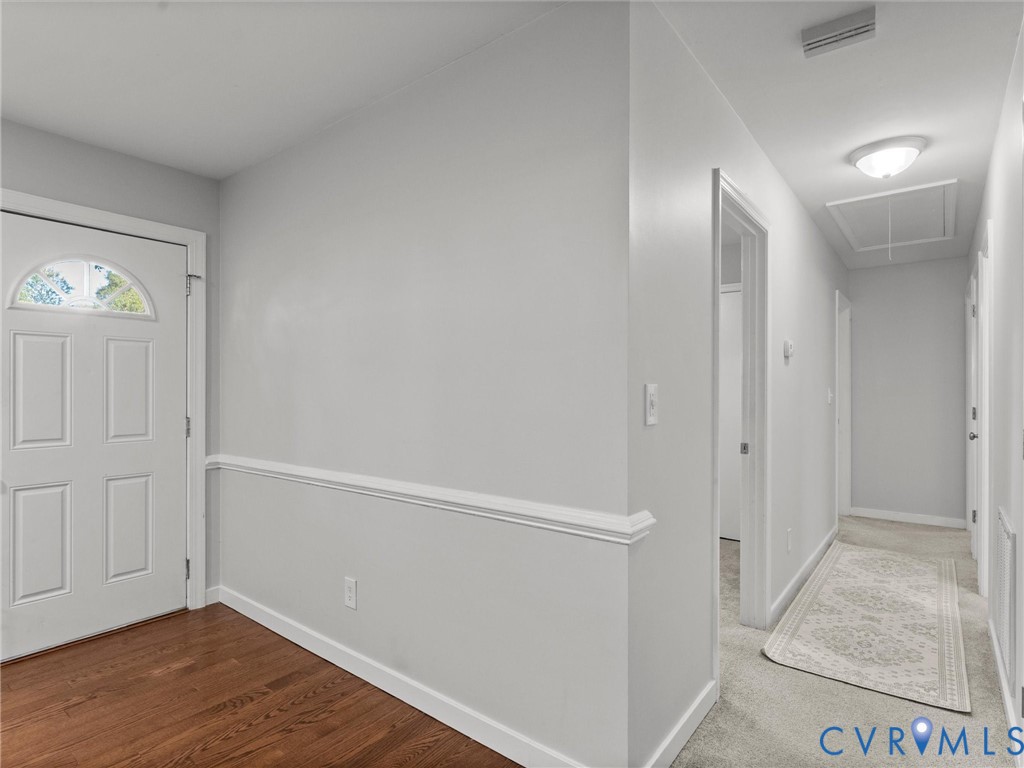 Entry featuring a white door with an arched window insert, wood-finish flooring, and chair rail molding