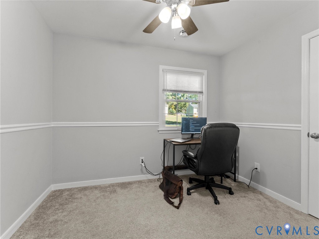 Neutral wall color featuring chair rail molding, wall-to-wall carpeting, single-hung window, and a ceiling-mounted fan with light fixture