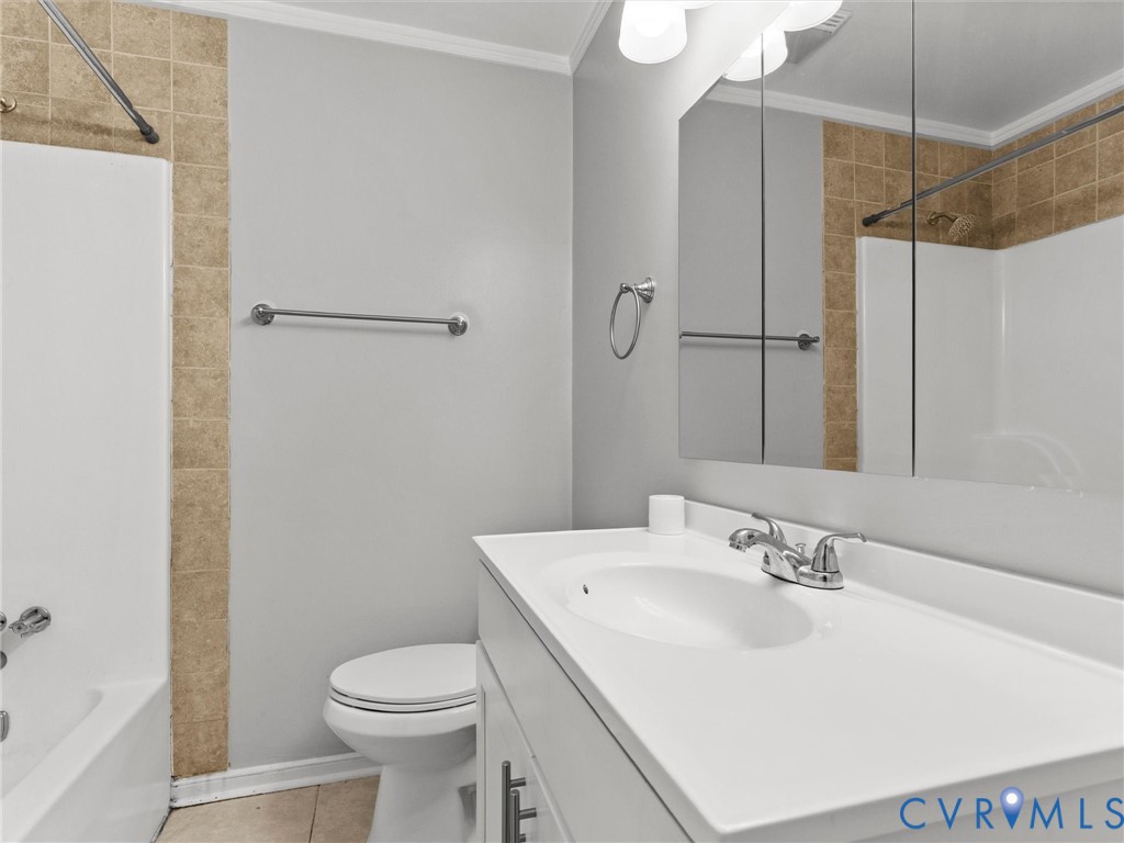 Bathroom featuring a vanity with integrated sink, tri-panel medicine cabinet, chrome fixtures, and a tub-shower combination with tile surround