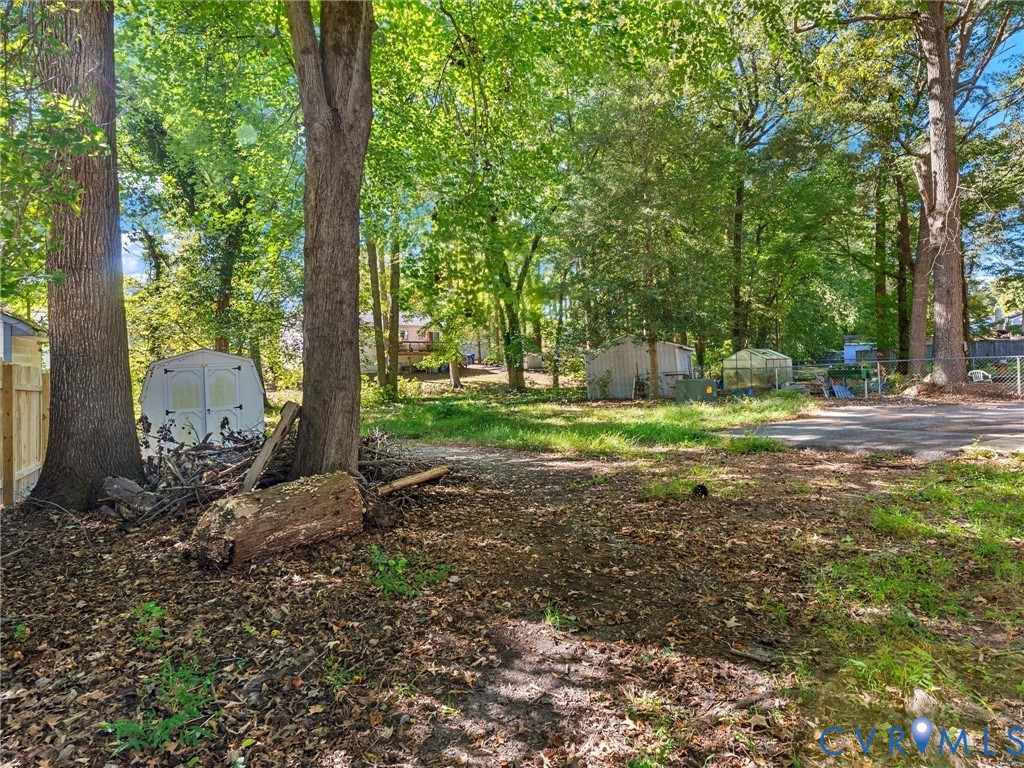 Expansive wooded lot featuring mature trees, a detached storage structure, and a fenced perimeter