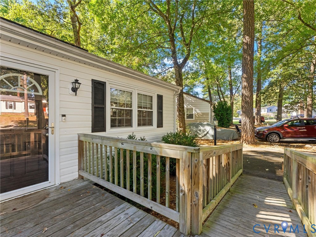 Exterior featuring horizontal siding, dark louvered shutters, wood-finish decking, and a wood-railing enclosure