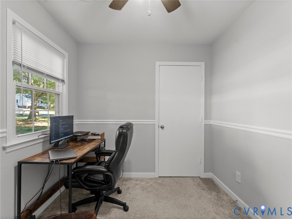 Neutral wall color with chair rail molding, wall-to-wall carpeting, window with pleated blinds, and ceiling fan with light fixture