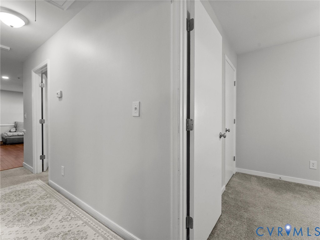 Neutral-toned interior featuring grey wall paint, plush carpeting, white interior doors with brushed nickel hardware, and a flush-mount ceiling light fixture