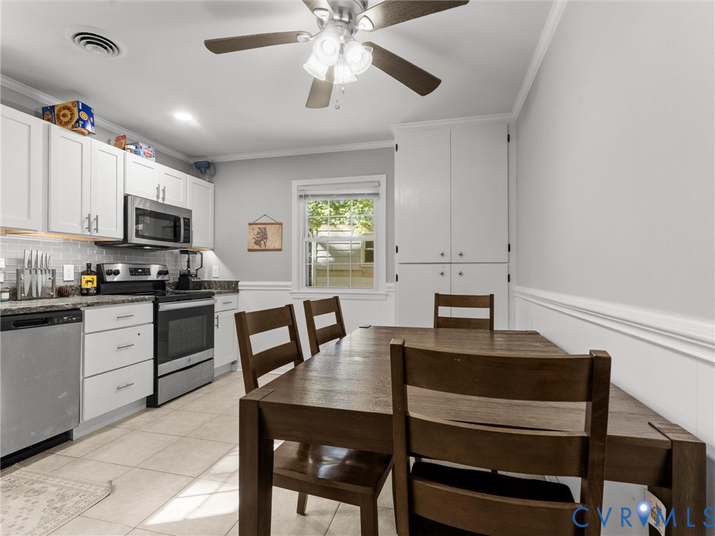 Kitchen featuring white cabinetry, stainless steel appliances, tile flooring, built-in floor-to-ceiling pantry storage, and a ceiling fan with integrated lighting